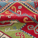 Folded edge and wool pile of red & green Kazak-inspired wool rug 24948.