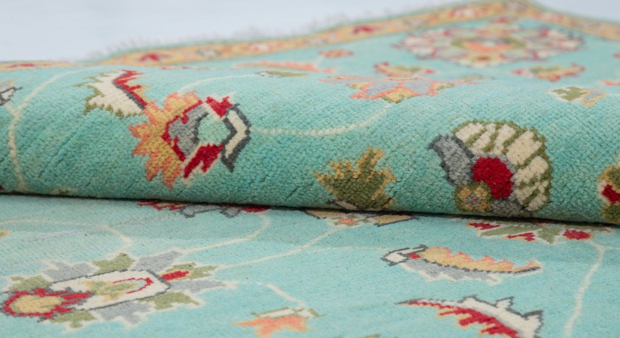 Folded edge and wool pile of turquoise & red Kazak-inspired wool rug 29664.