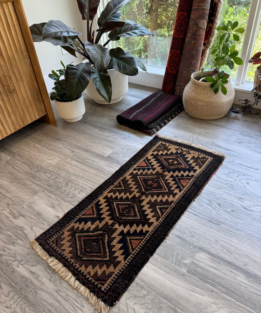 Antique Baluch bag face rug runner with navy, tan, and red geometric center medallion