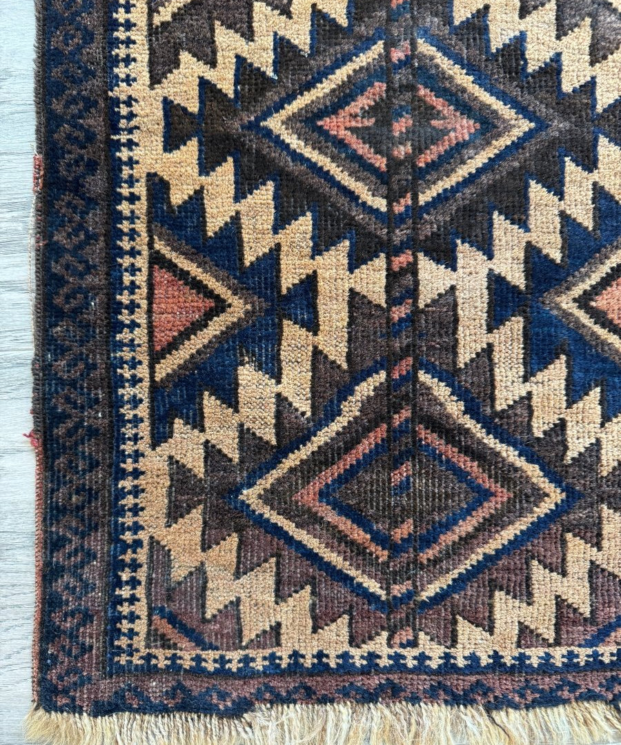 Antique Baluch bag face rug with navy, cream, and red geometric diamond pattern