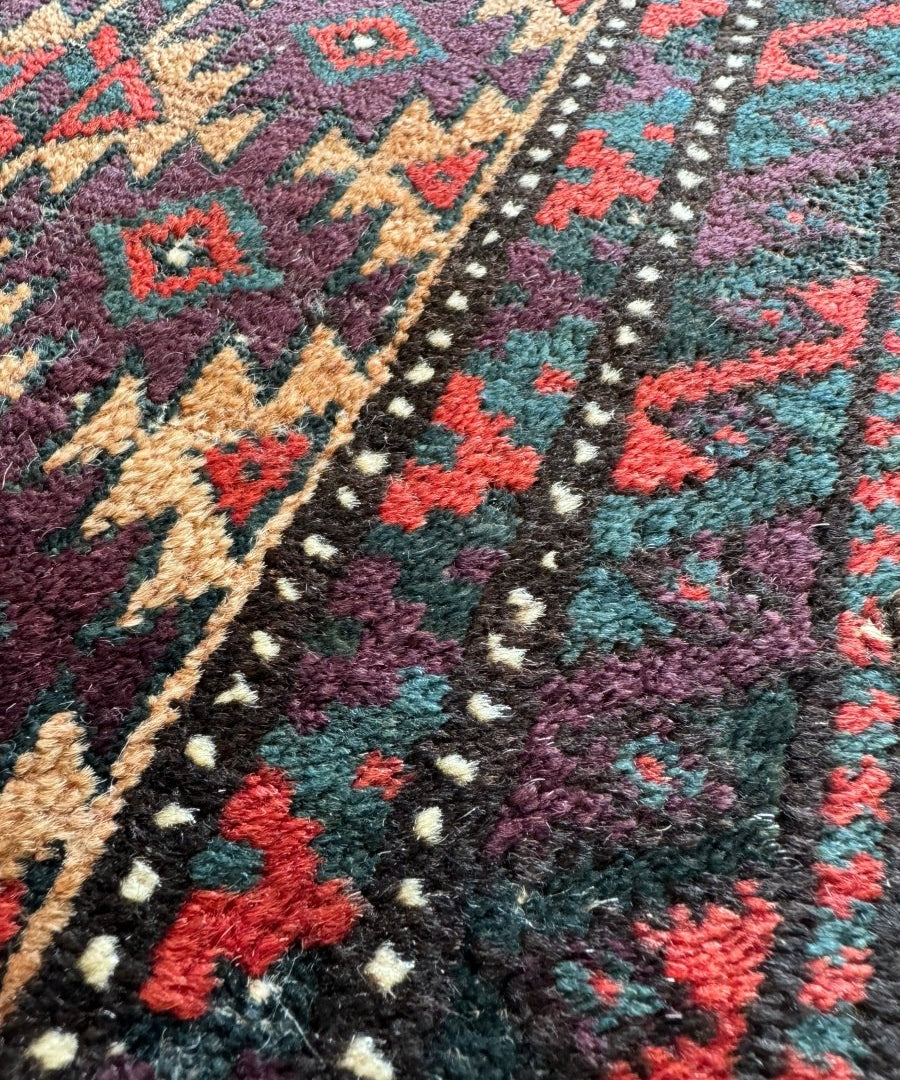 Close-up of Baluch bag face rug pile with teal, red, and cream geometric motifs