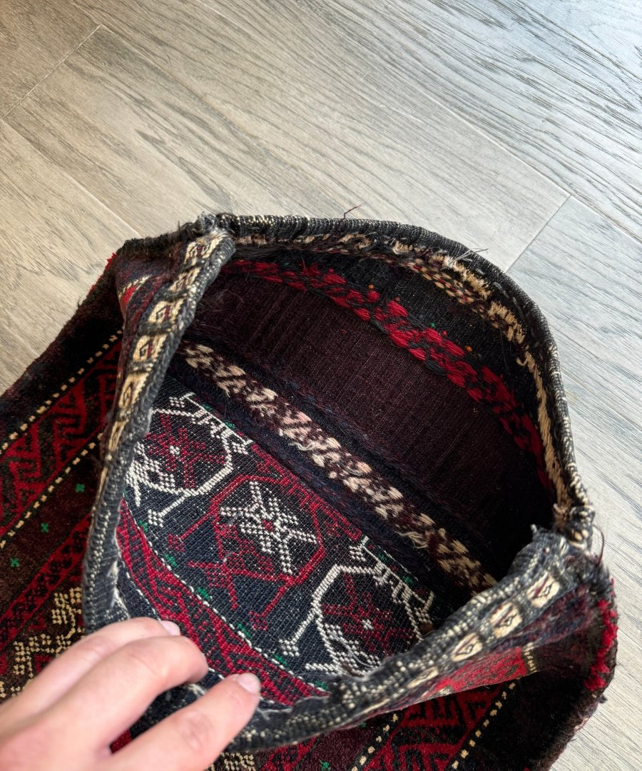 Antique Baluch saddlebag with open pocket and patterned lining inside; dark trim edges