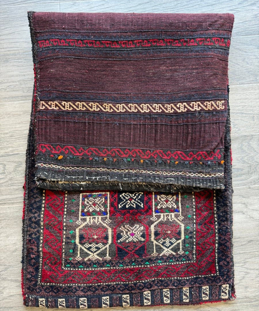 Antique saddlebag with maroon top panel, dark border, and central red-and-cream motif