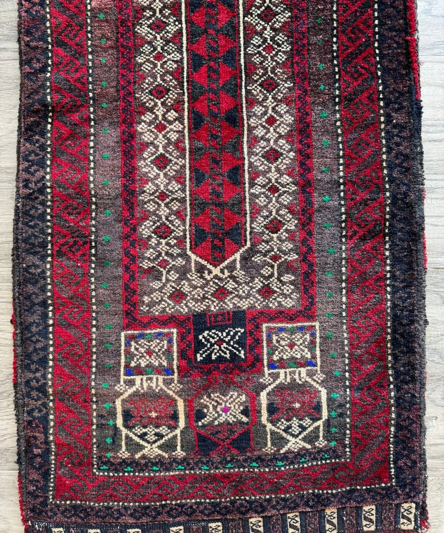 Antique saddlebag rug panel with red, navy, and cream geometric patterns and border trim