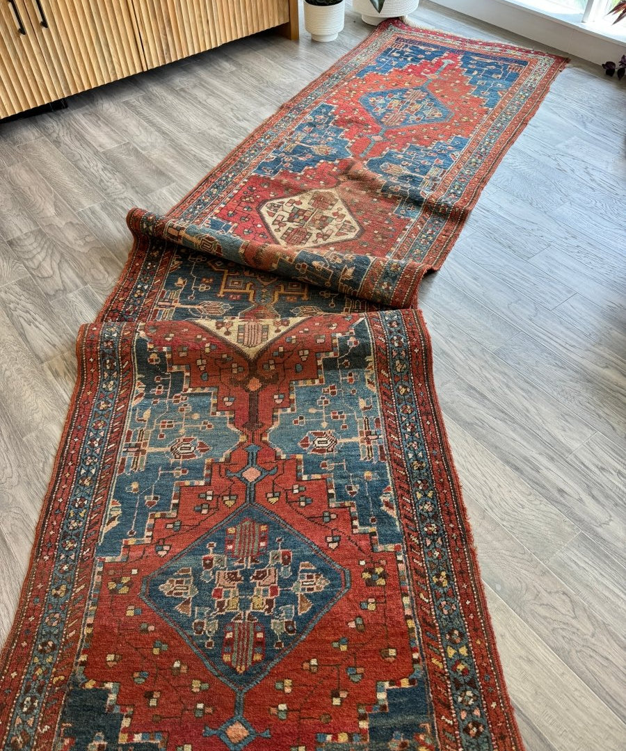 Antique Bidjar runner rug in red, blue, and rust laid on wood floor