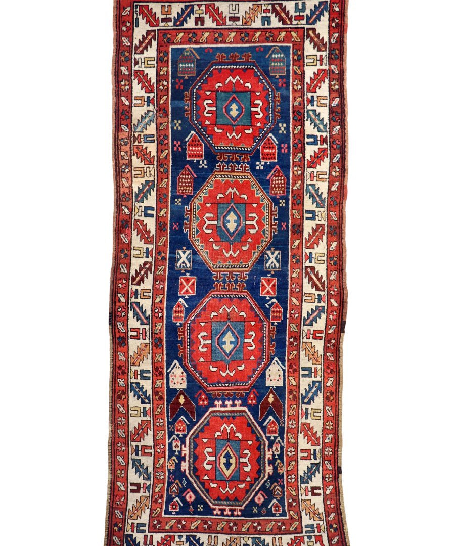 Full antique Kazak rug with red, blue, and cream medallions on white background