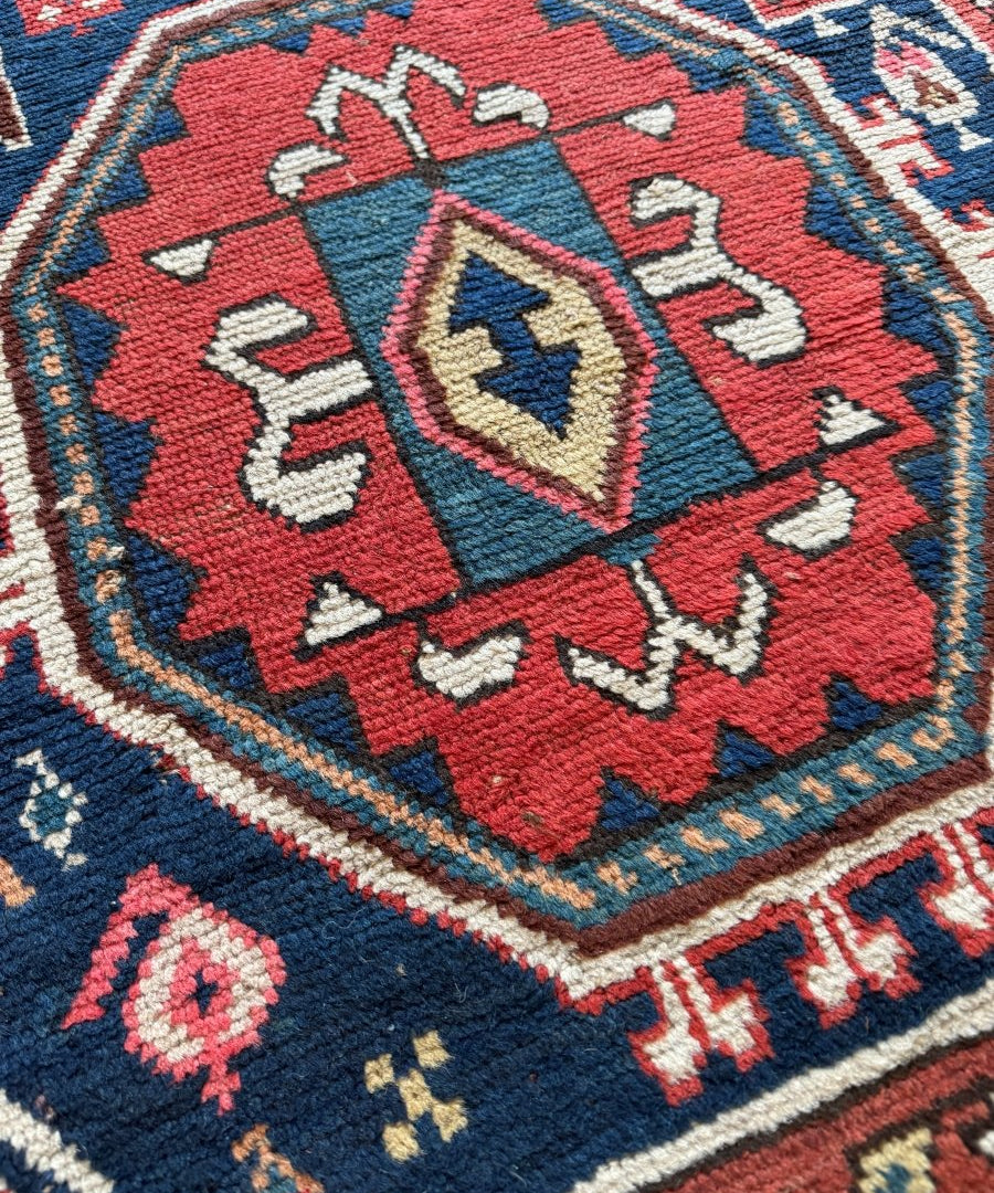Close-up of Kazak rug medallion in red with blue corner details and cream accents