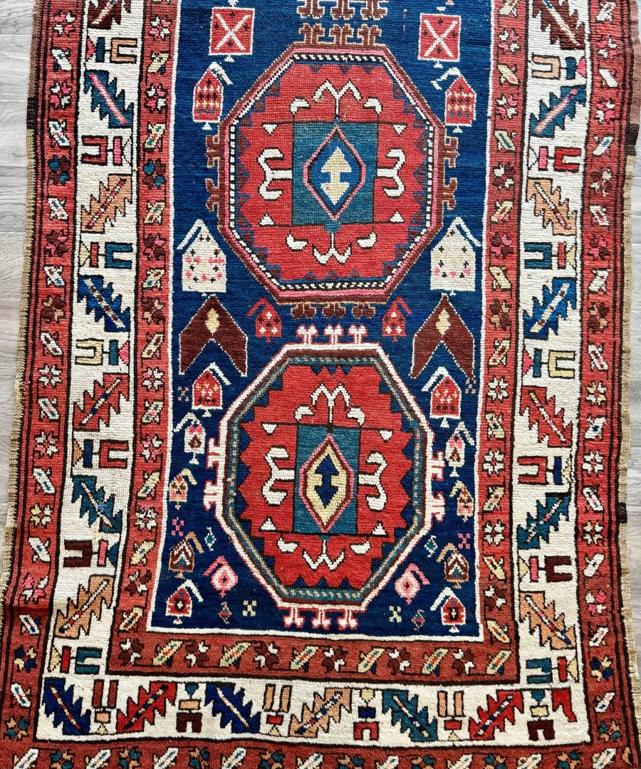 Antique-style Kazak rug with red, blue, and cream geometric medallions and borders