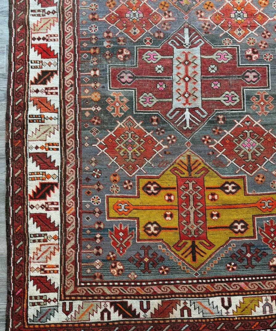 Antique Kazak rug with red, navy, cream, and multicolor geometric border and fringe edge