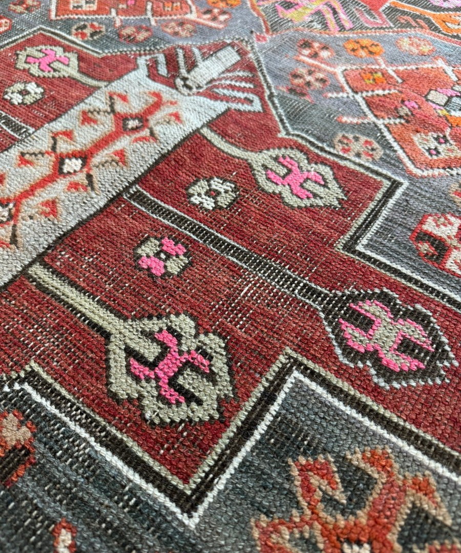 Antique Kazak rug close-up showing red and gray-blue panel with small diamond details