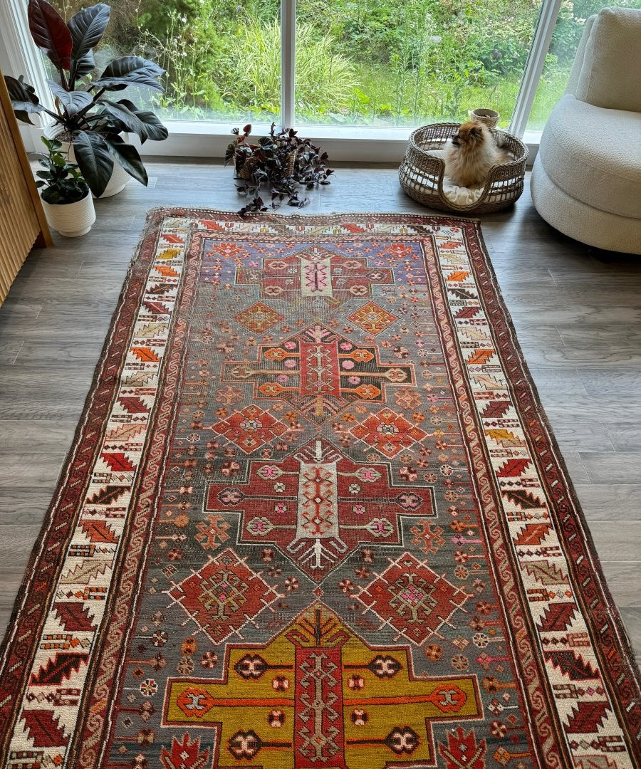 Antique Kazak rug laid flat with red, rust, gray-blue, and cream medallion pattern