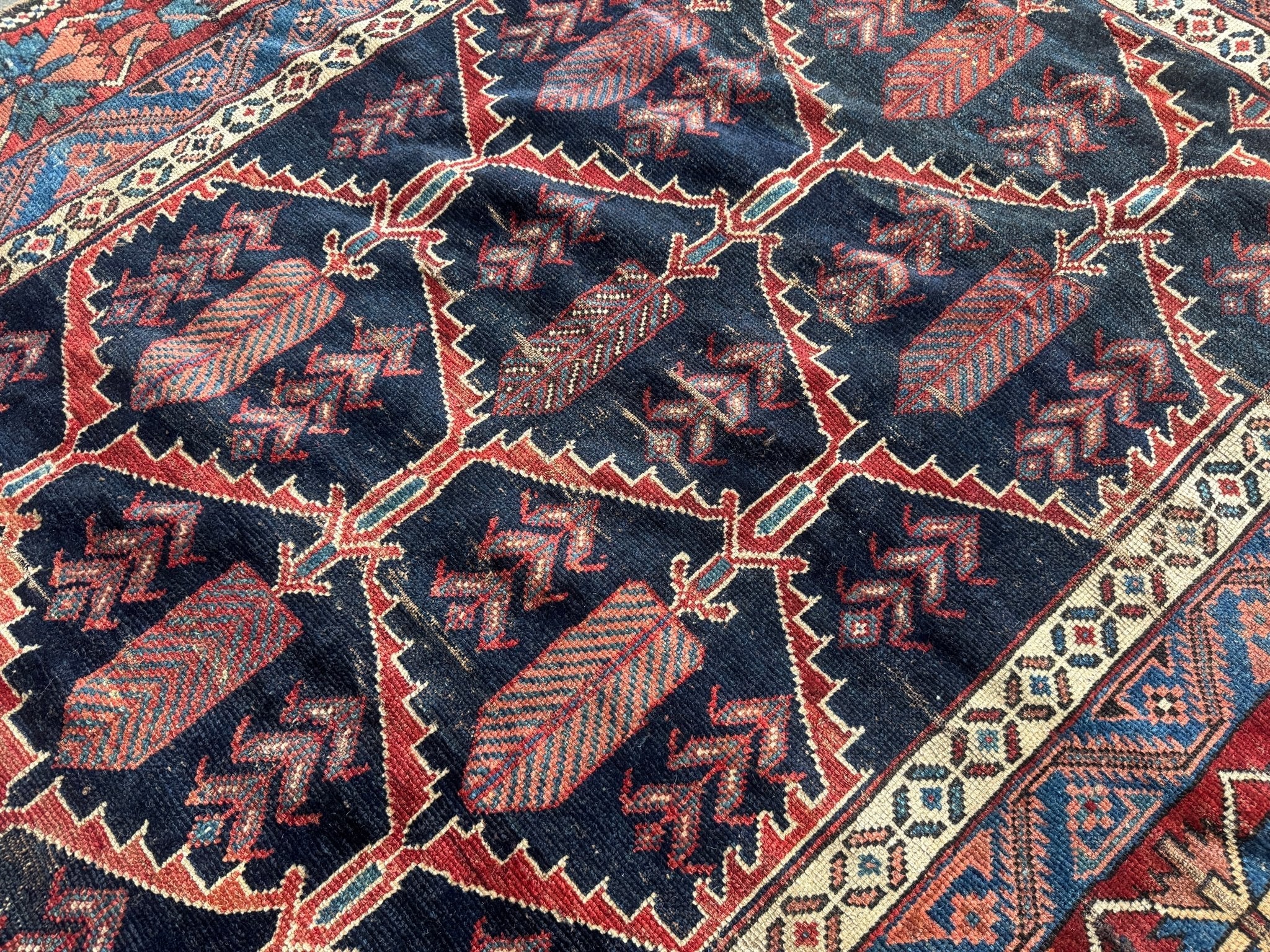 Antique Persian Bakhtiari rug close-up with dark navy lattice and red diamond motifs.