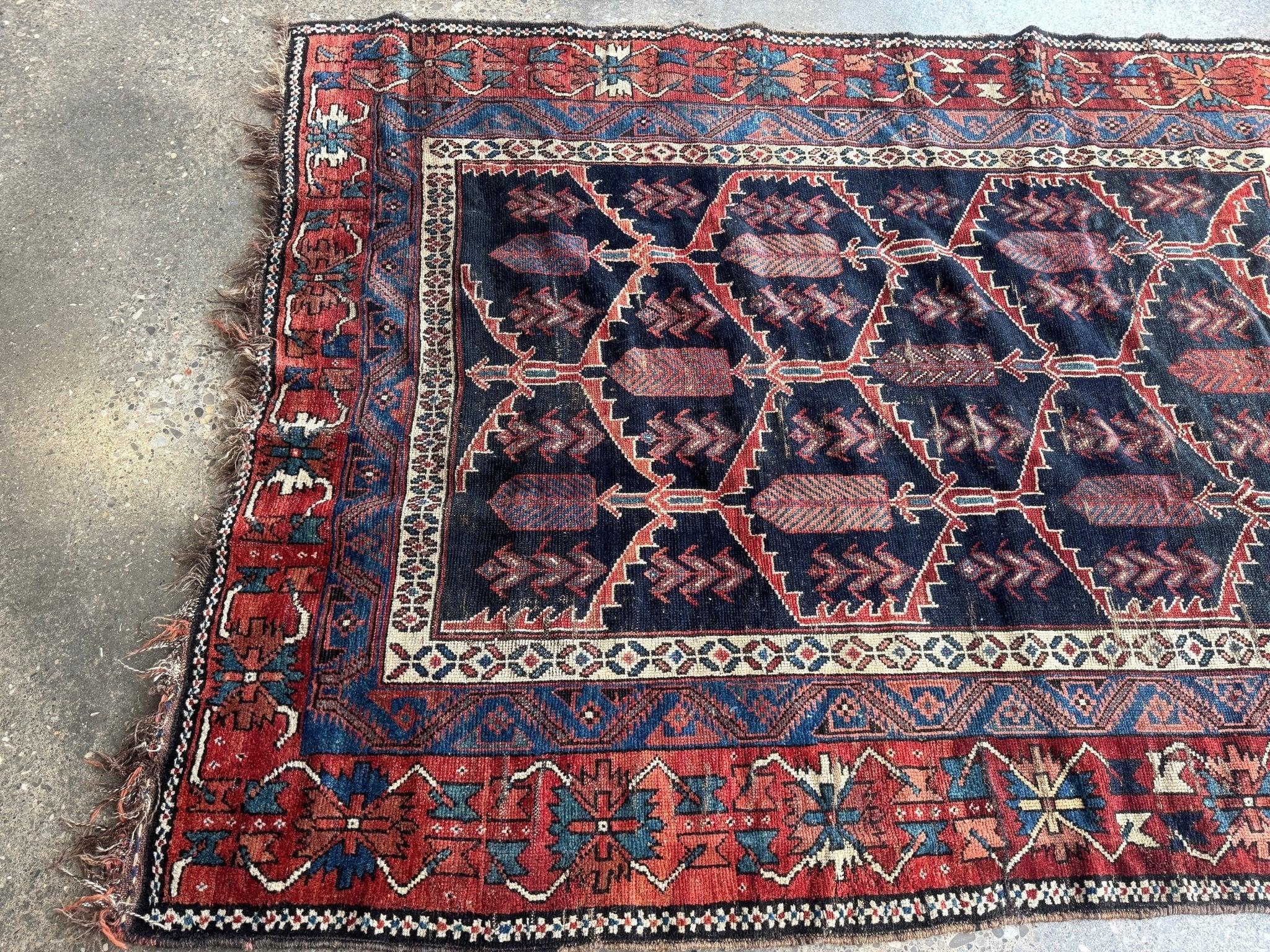Antique Persian Bakhtiari rug corner detail with navy center, red accents, and cream trim.
