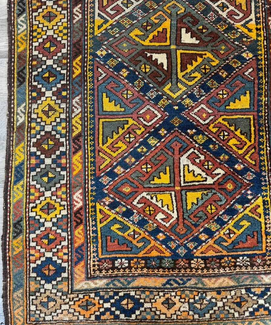 Geometric runner rug with navy, rust, and yellow motifs; ornate border and medallion design.