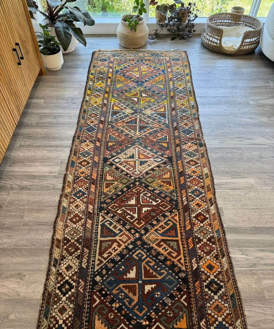 Navy and rust antique runner rug with dense geometric patterns and border trim along edges.