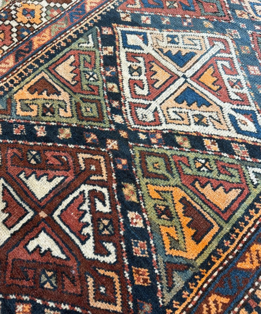 Close-up of geometric runner rug in blue, cream, rust, and multicolor accents; detailed motifs.