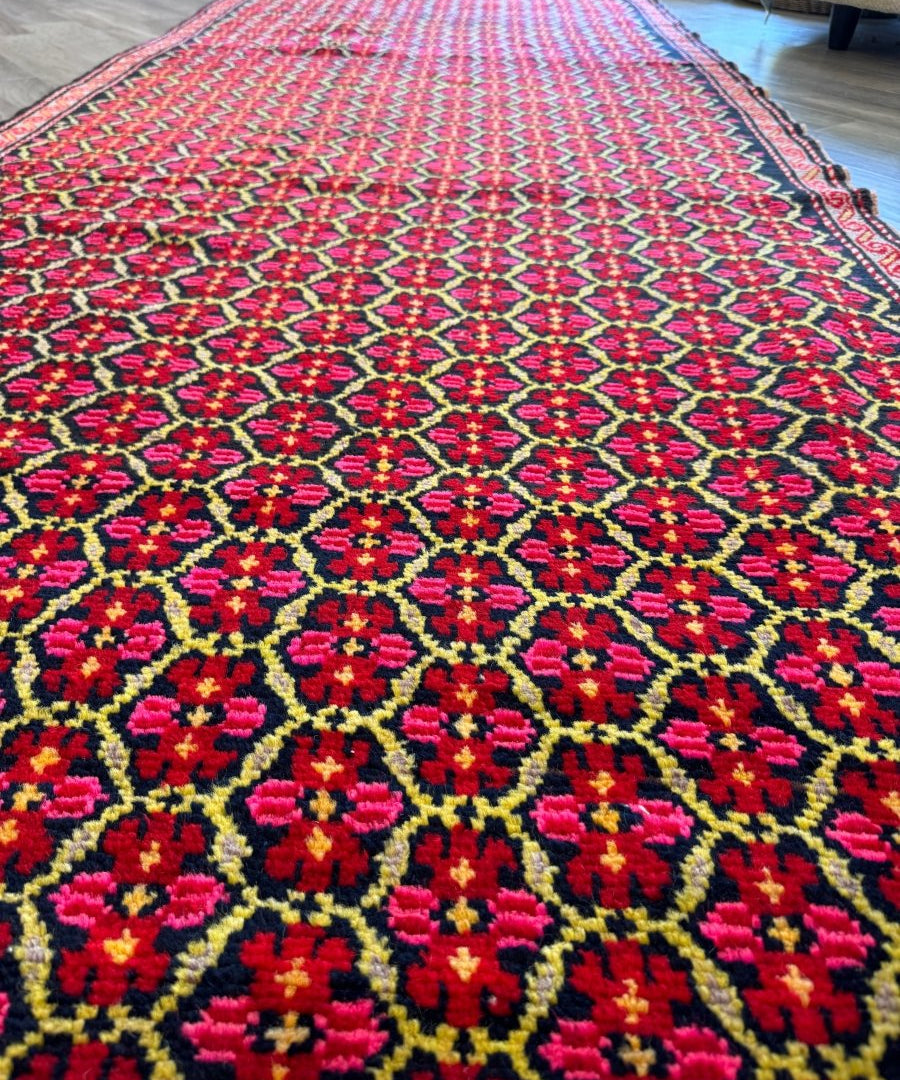 Detail of red runner rug with navy border and symmetrical floral diamond lattice pattern