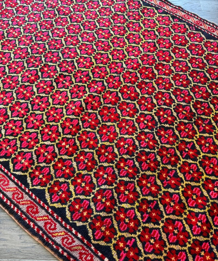 Close-up of Persian-style runner rug with red flowers, navy ground, and yellow accents