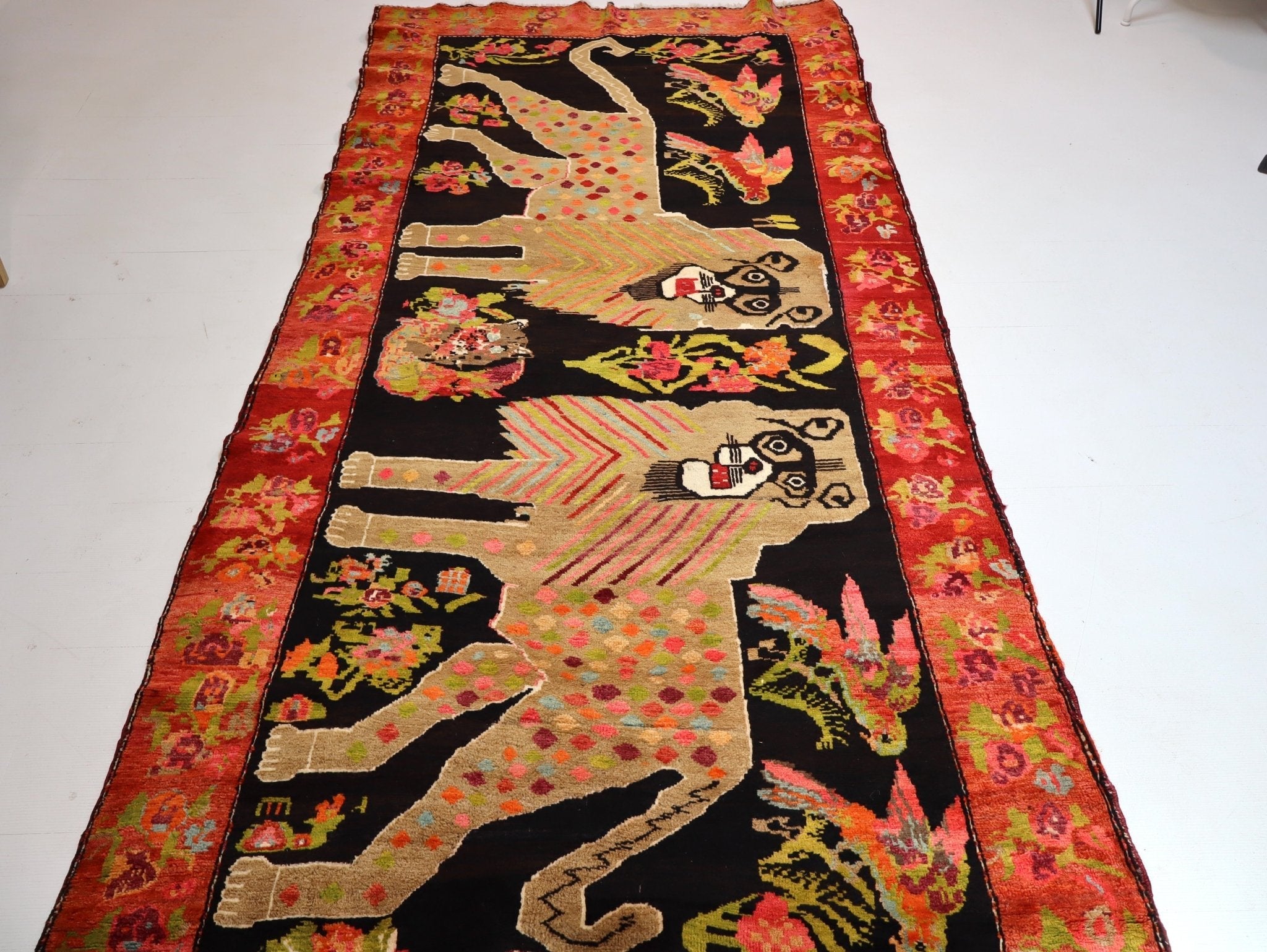 Patterned area rug with black background, red border, and stylized animal figures