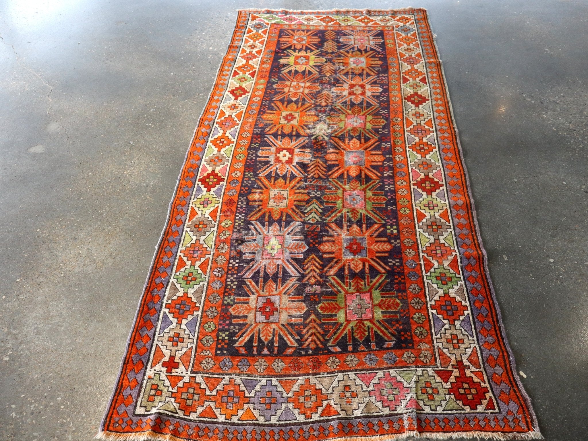 Geometric runner rug in orange, navy, cream with central medallion and patterned border