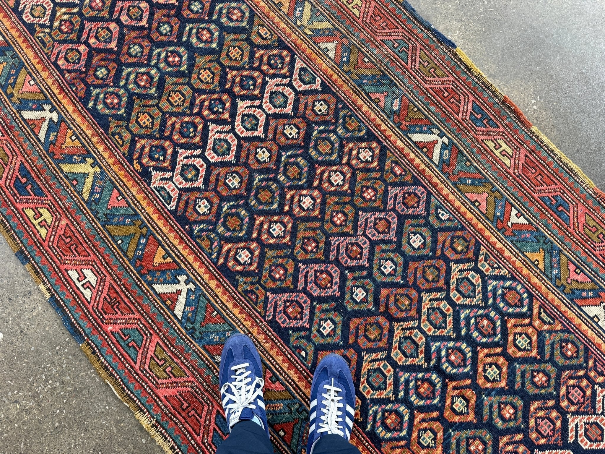 Kazak runner rug runner with dark blue geometric lattice, red side border, and cream accents.