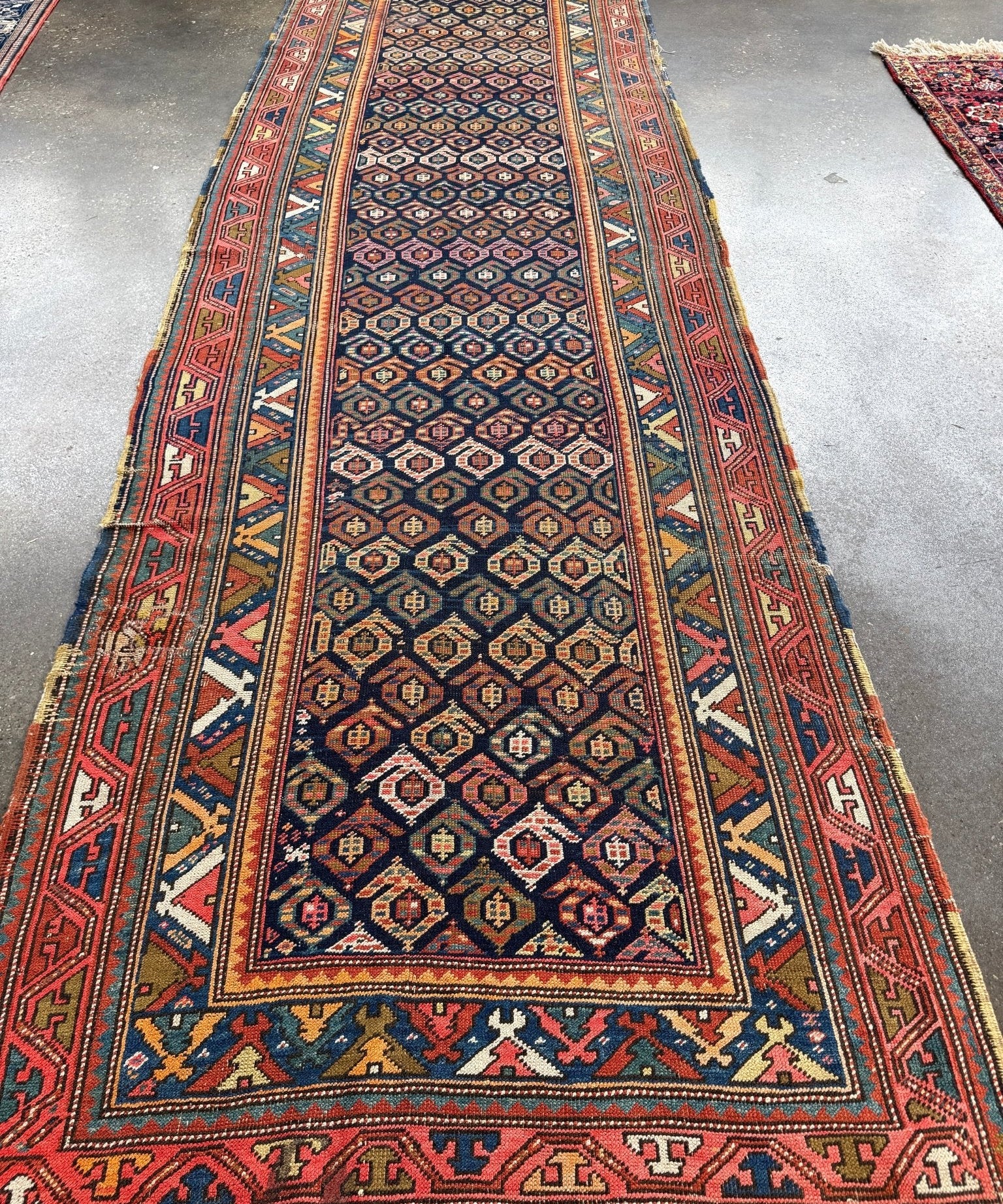 Navy blue runner rug with red border and geometric medallion pattern, long rectangular