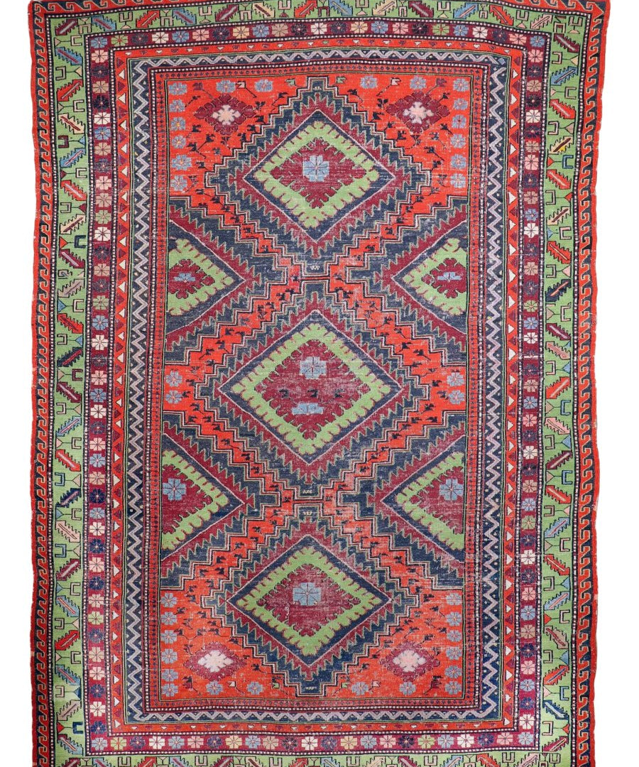 Soumak rug with red central medallion, blue geometric zigzags, green side panels and border