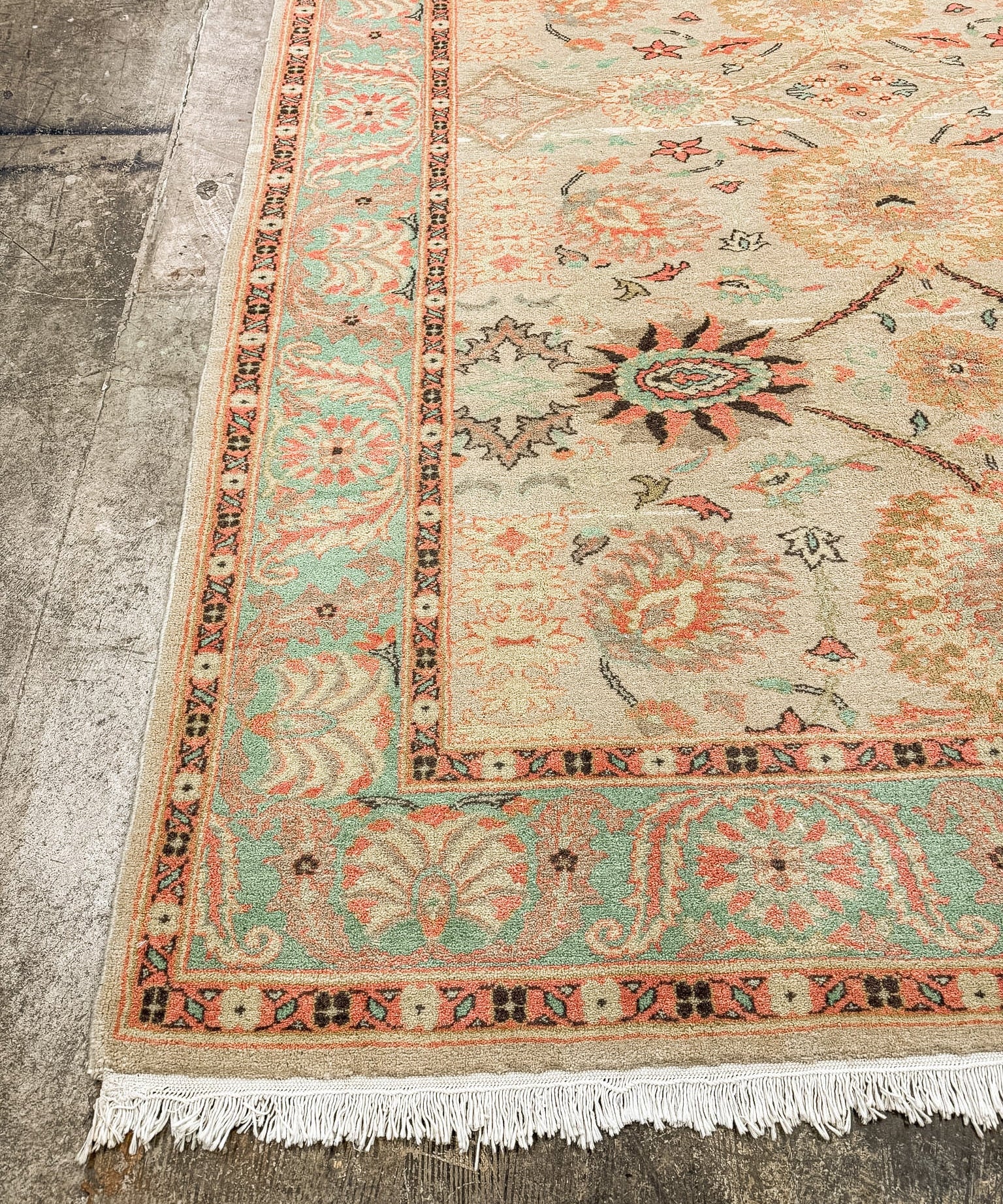 Sultanabad rug edge with teal border stripe, coral motifs, floral field, and fringe