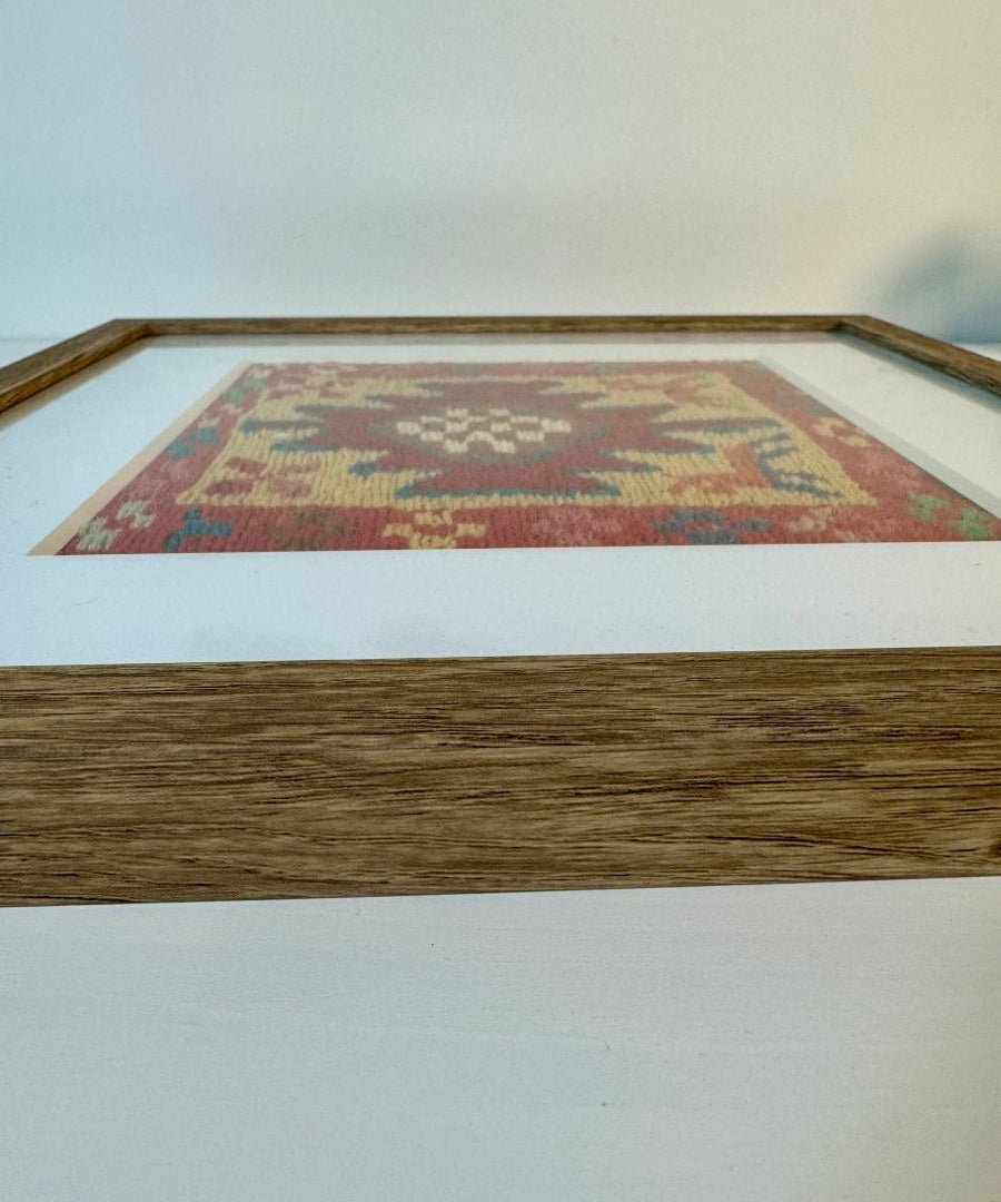 Framed kilim rug viewed from side, red patterned textile set in a wooden frame.