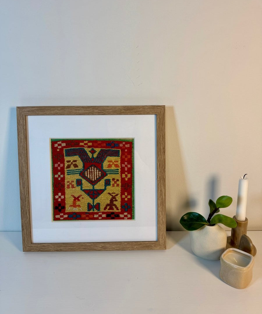 Framed small kilim wall art with red geometric pattern and blue diamond center.