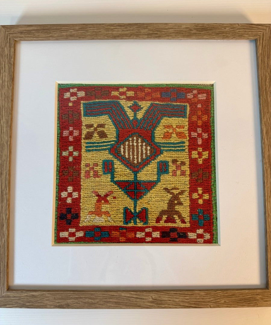 Framed kilim wall art with red background and yellow, blue geometric diamond motif.