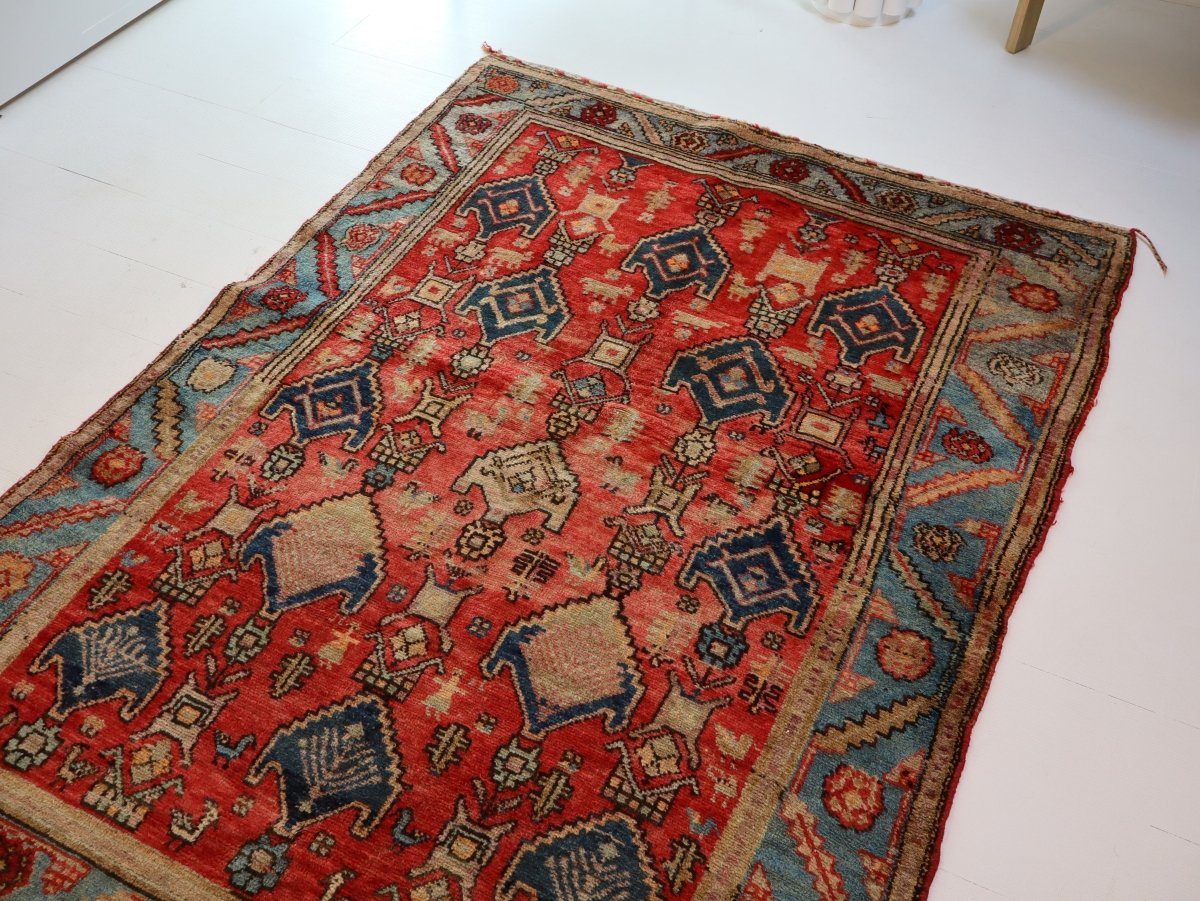 Rectangular rug with red field, blue border, and centered cream diamond and motifs