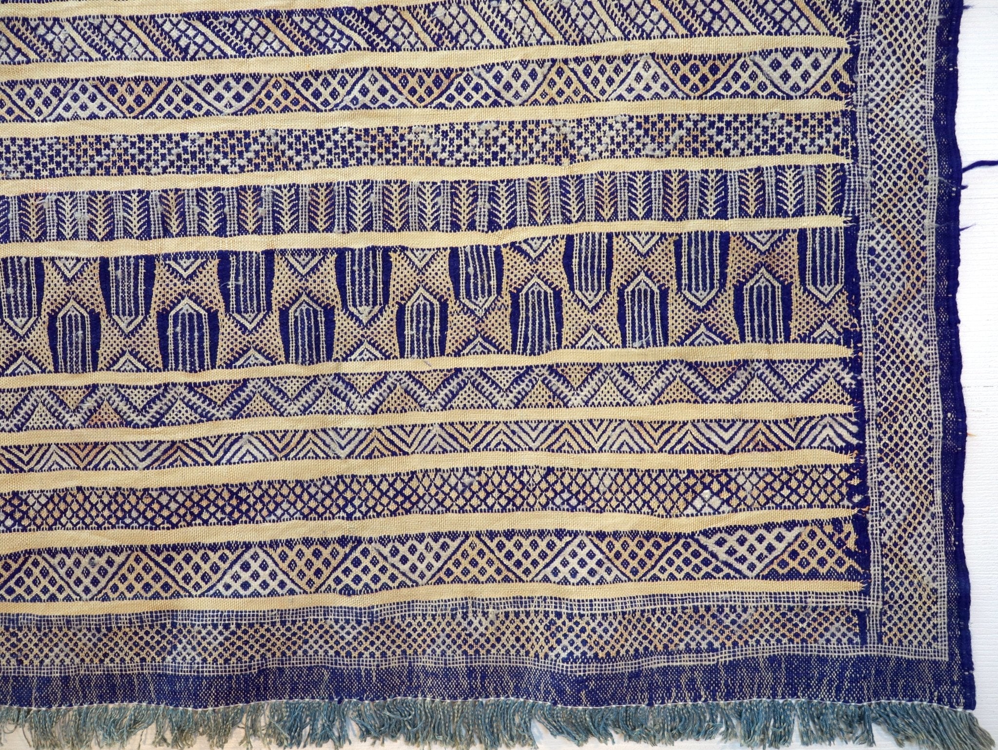 Blue and cream kilim rug detail with repeating patterns and navy fringe edge