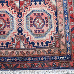 Persian runner rug corner with red and navy medallions and short fringe edge