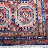 Persian runner rug corner with red and navy medallions and short fringe edge