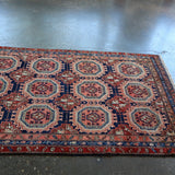Persian-style runner rug corner view with red border and blue geometric lattice