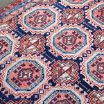 Persian-style runner rug close-up with red, blue, and cream diamond and octagon motifs