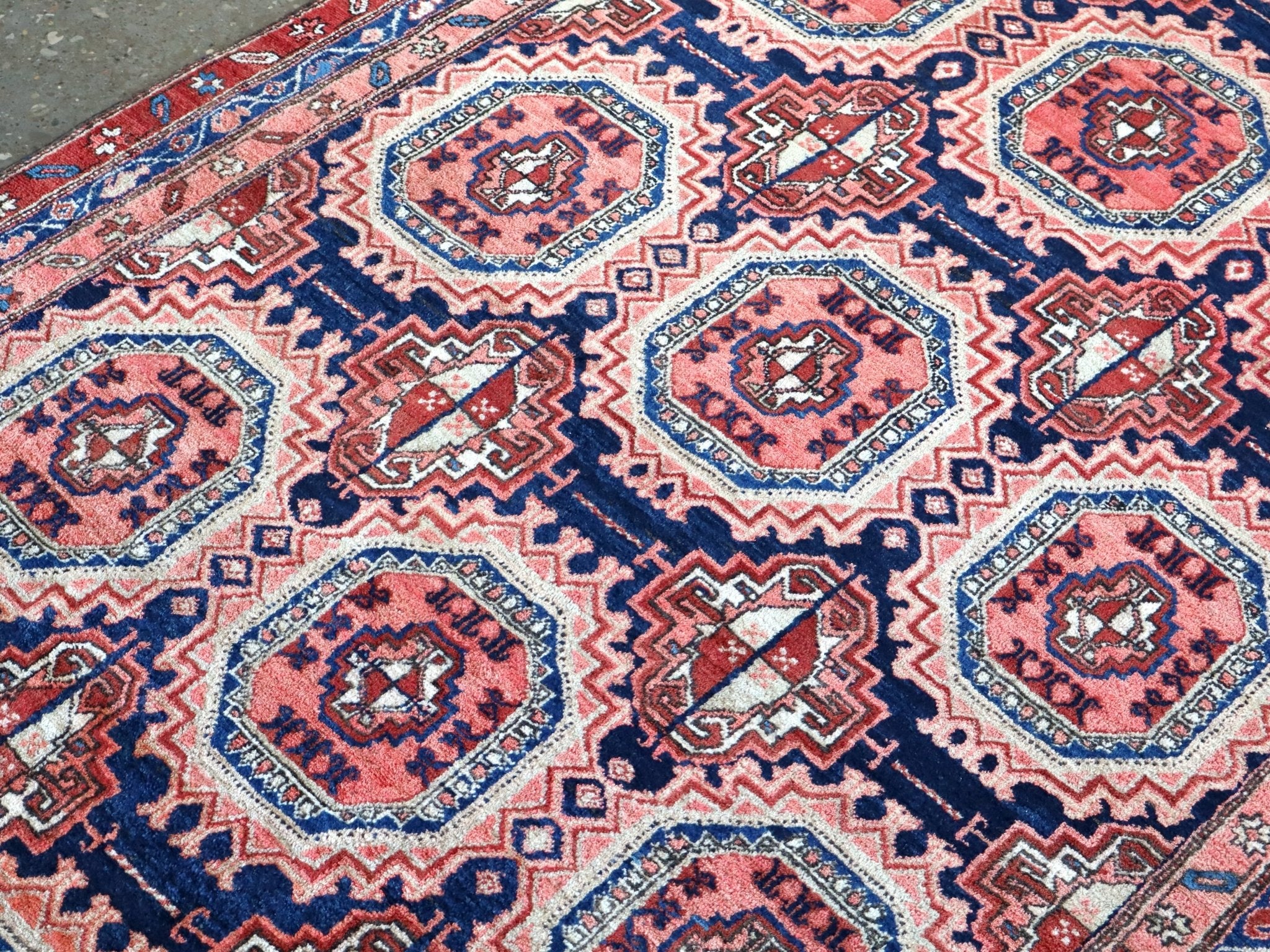 Persian-style runner rug close-up with red, blue, and cream diamond and octagon motifs