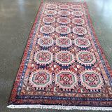 Persian-style meshkin runner rug with repeating octagon motifs in red, blue, cream