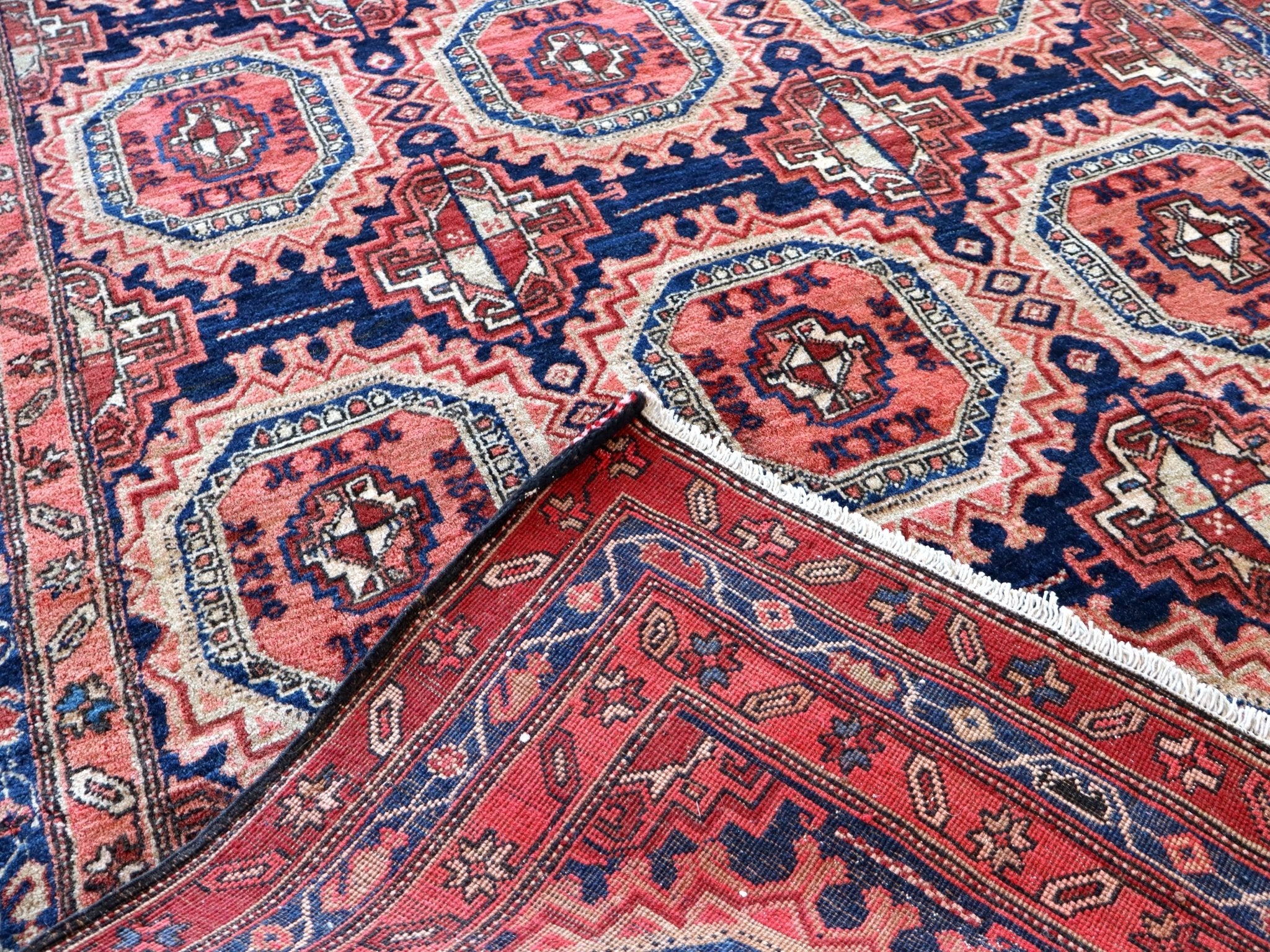 Persian runner rug close-up of rosette medallions and zigzag border in navy red