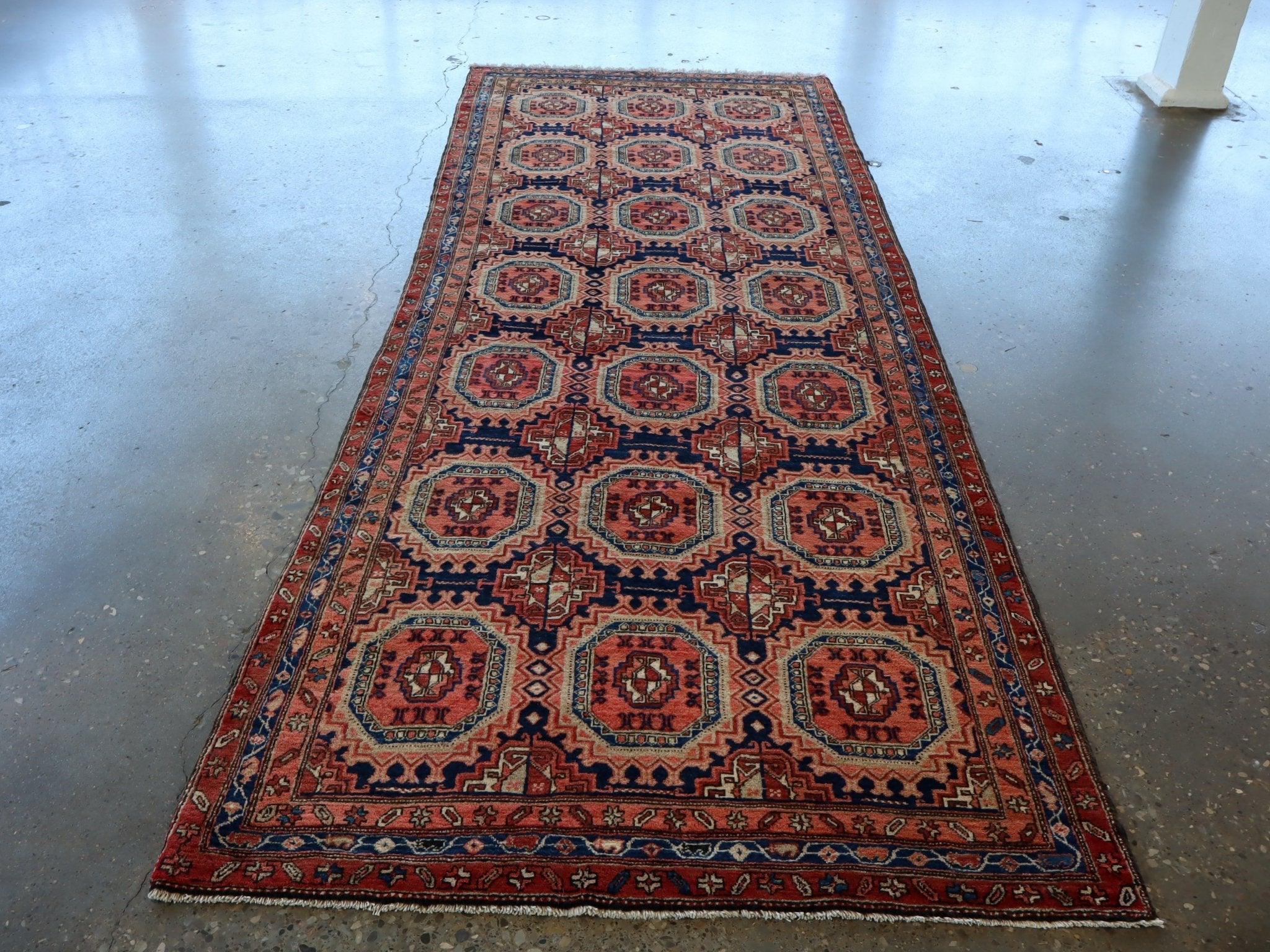 Persian-style runner rug full view with red border and navy geometric medallions