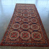 Persian-style runner rug full view with red border and navy geometric medallions