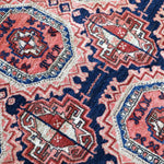 Persian runner rug close-up showing red medallions and navy border details