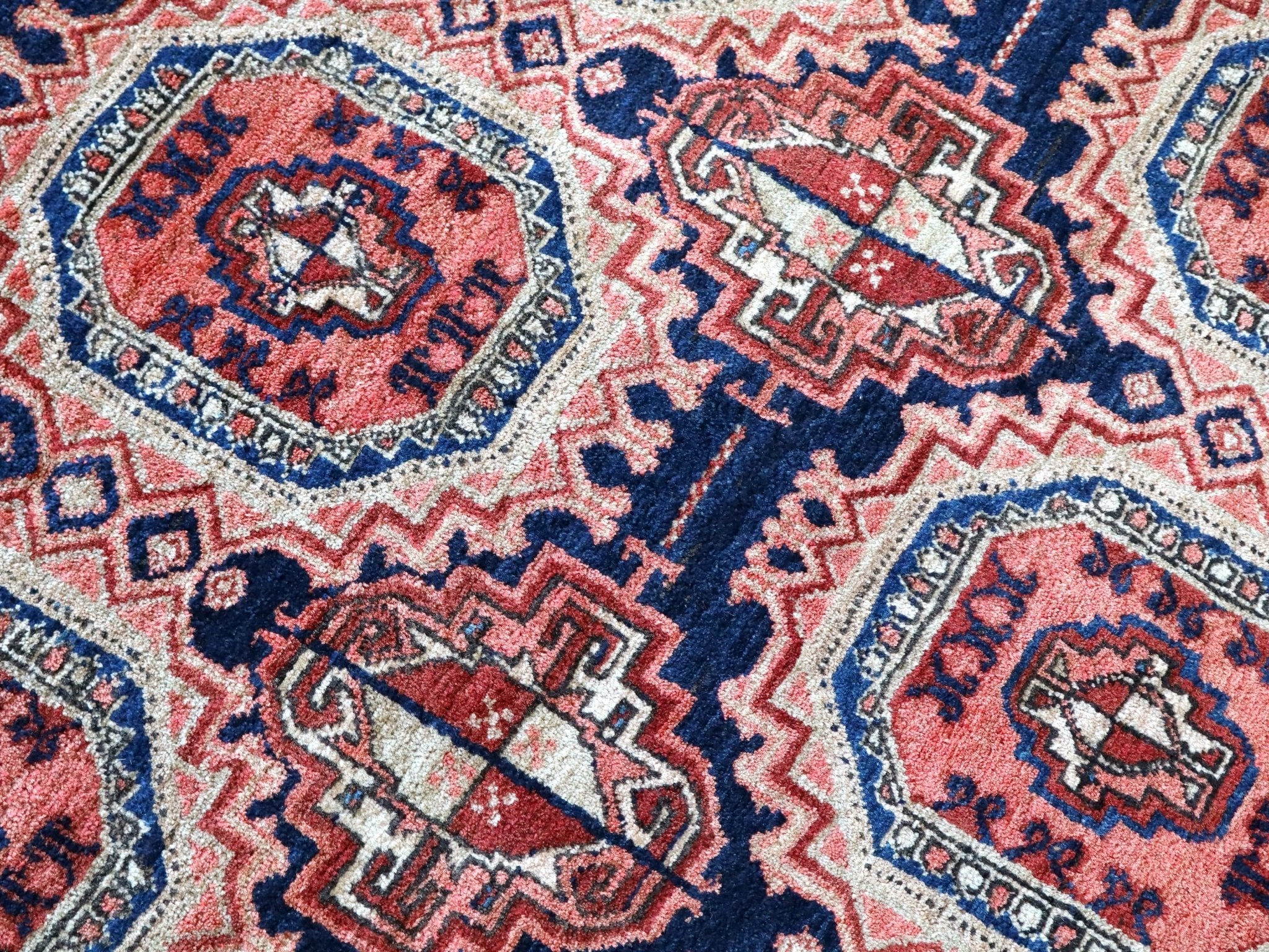 Persian runner rug close-up showing red medallions and navy border details