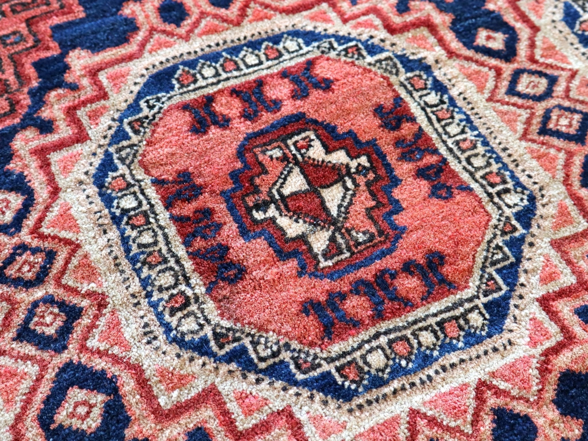 Persian-style runner rug center medallion close-up in red, blue, and cream