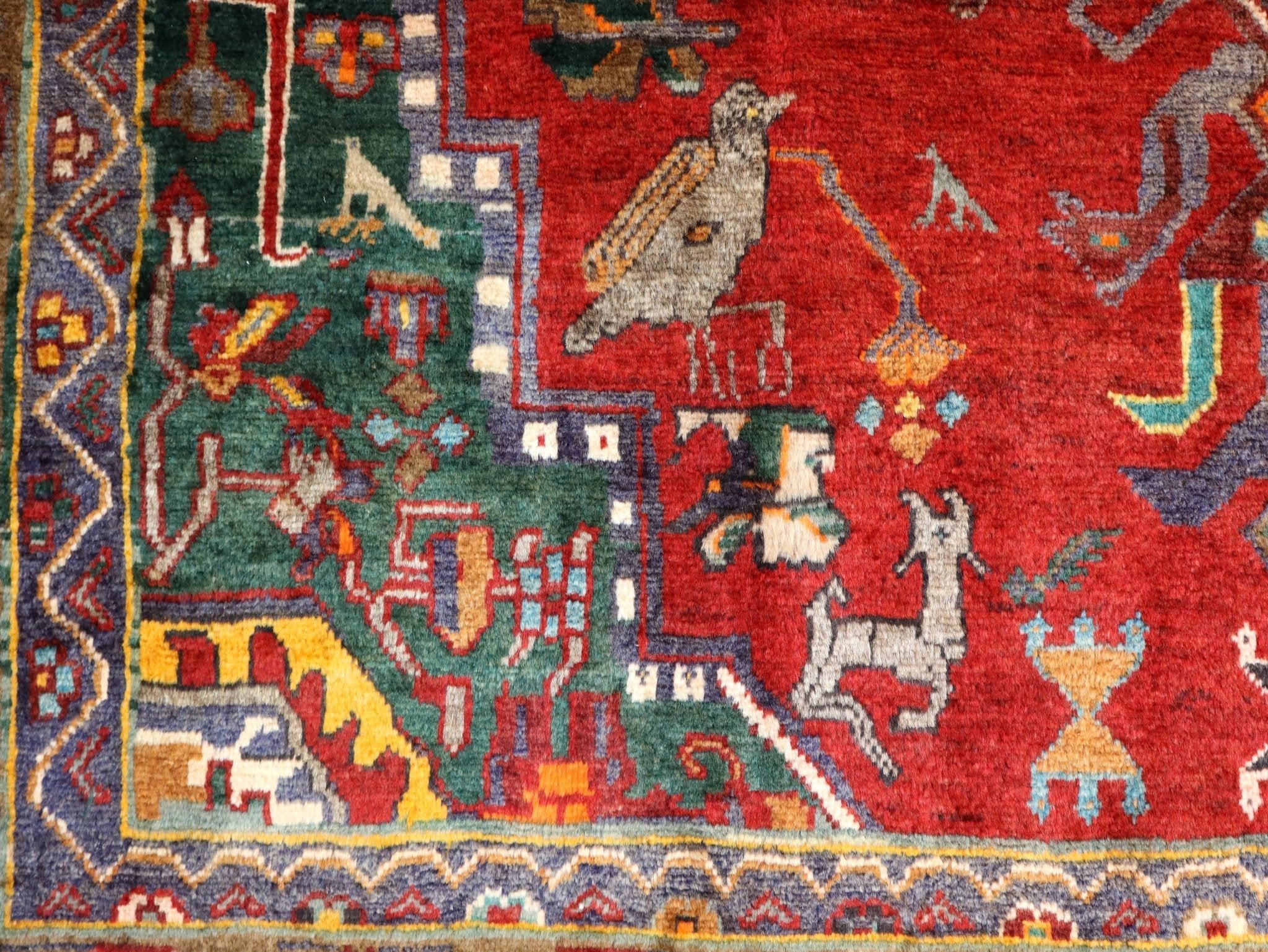 Close-up red Persian-style rug with multicolor geometric motifs in blue, green, yellow.