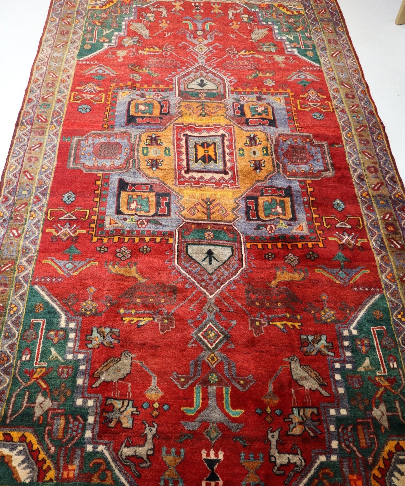 Red Persian-style rug full view with central medallion, multicolor border, and geometric motifs.