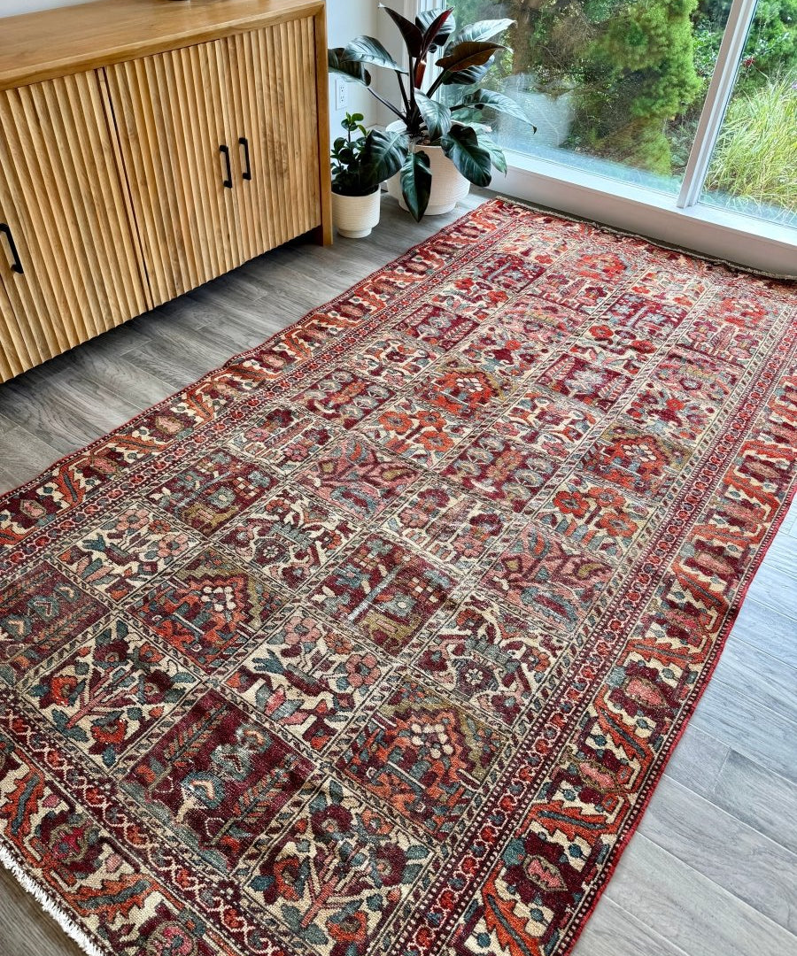 Perisan Bakhtiari rug laid flat with red, cream, blue, and burgundy patterning and fringe.