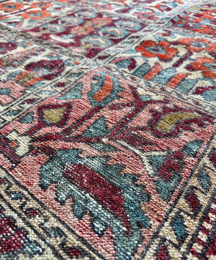 Perisan Bakhtiari rug close-up showing teal, red, and cream vines and geometric details.