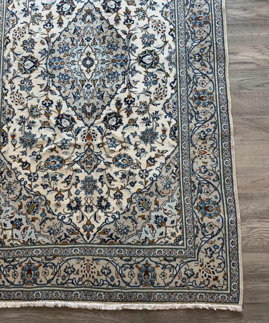 Ivory Kashan-style area rug with blue vine motifs and detailed border